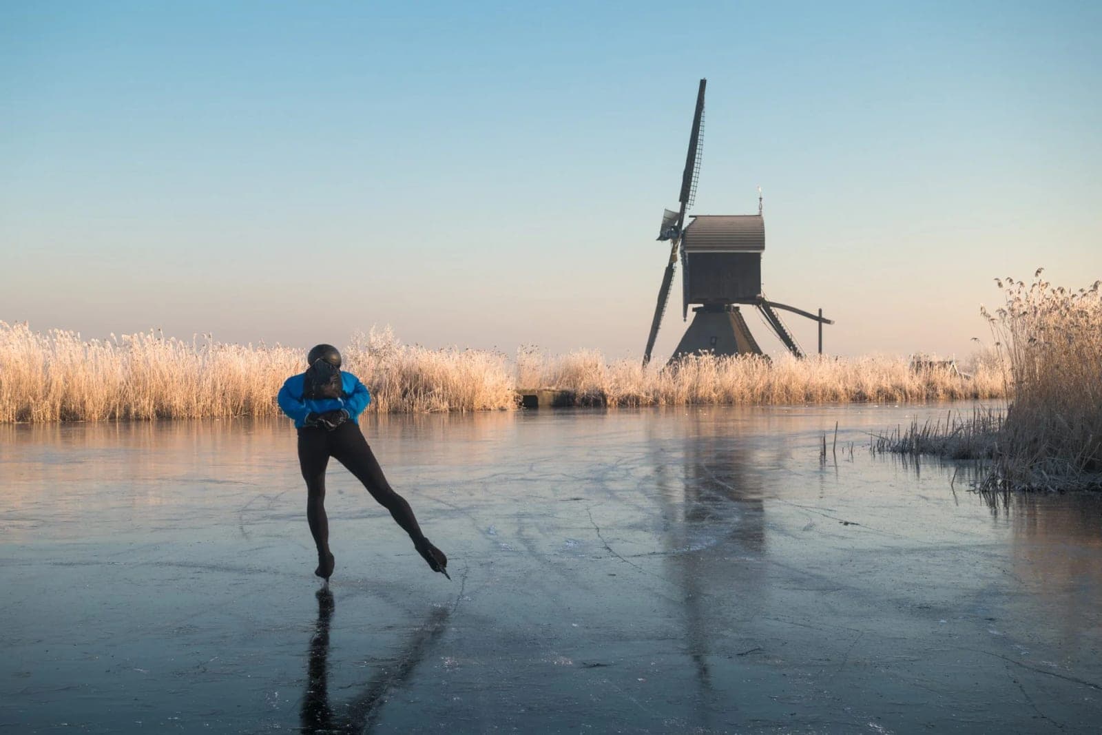 Schaatsers op natuurijs langs berijpt riet
